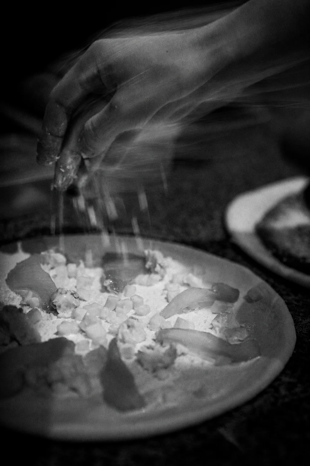Pizza toppings being finished by hand in expressive black and white at Billy’s Pizza
