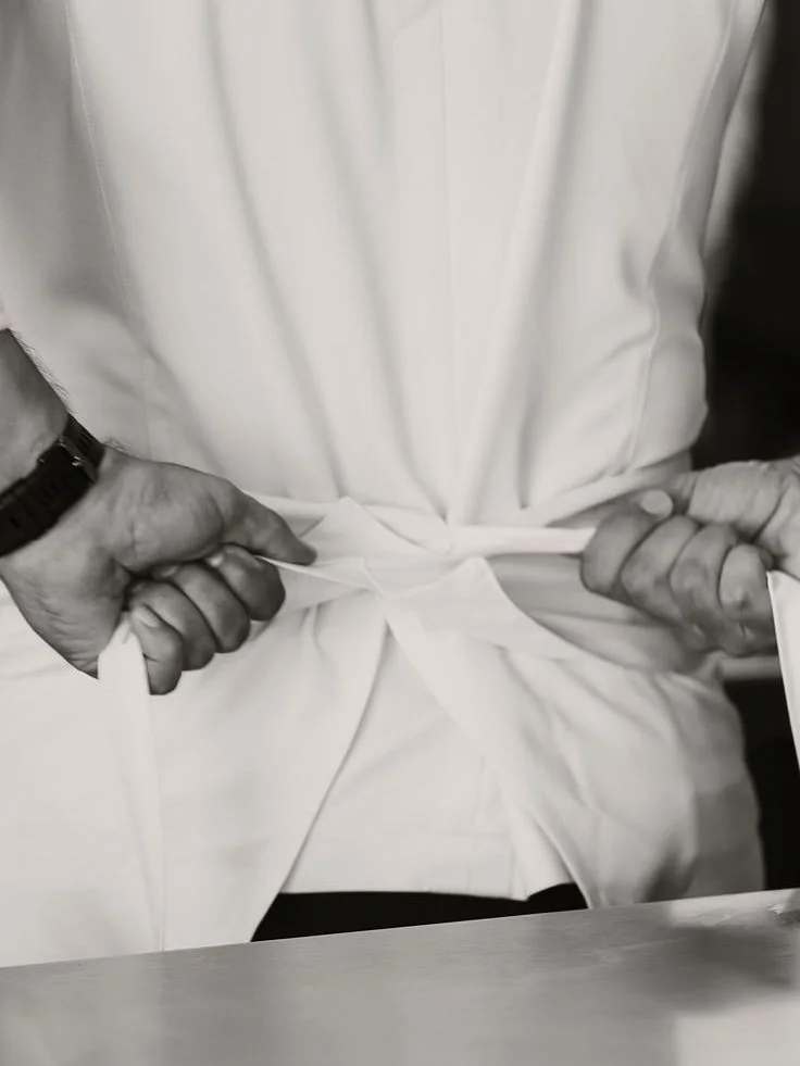 Chef tying an apron before service in black and white