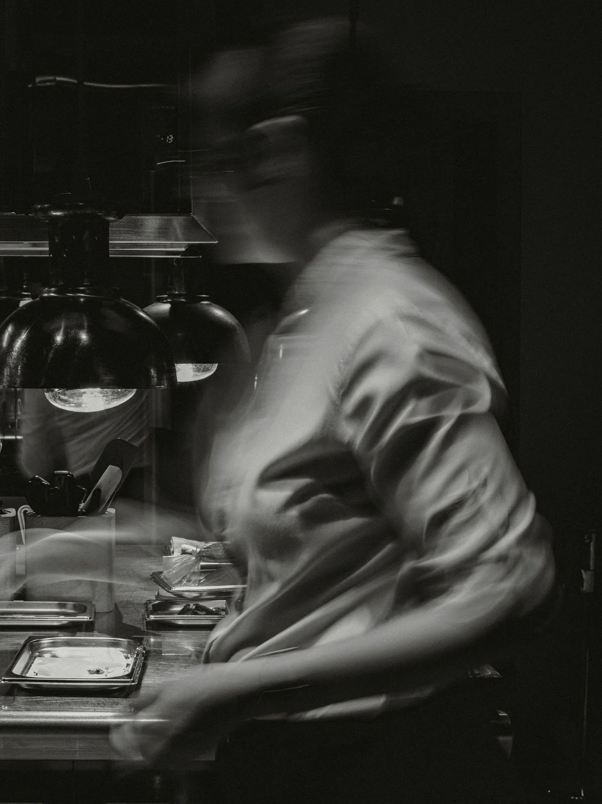 Chef moving through the kitchen in expressive monochrome