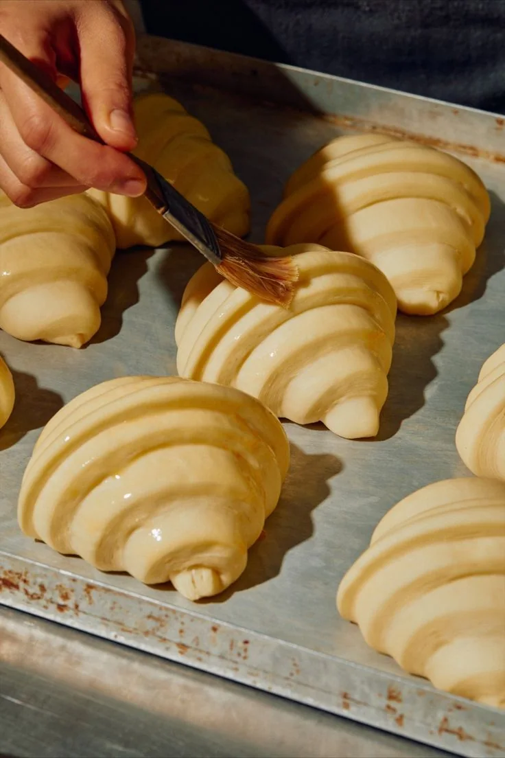 Brushing croissants before baking