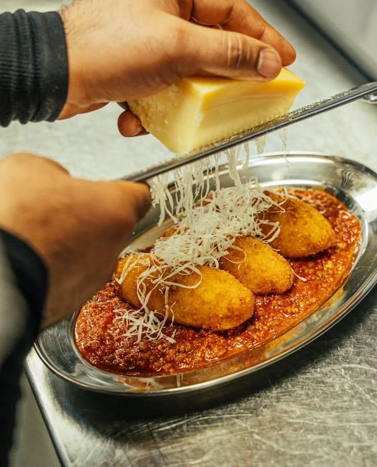 Finishing a restaurant dish with freshly grated cheese