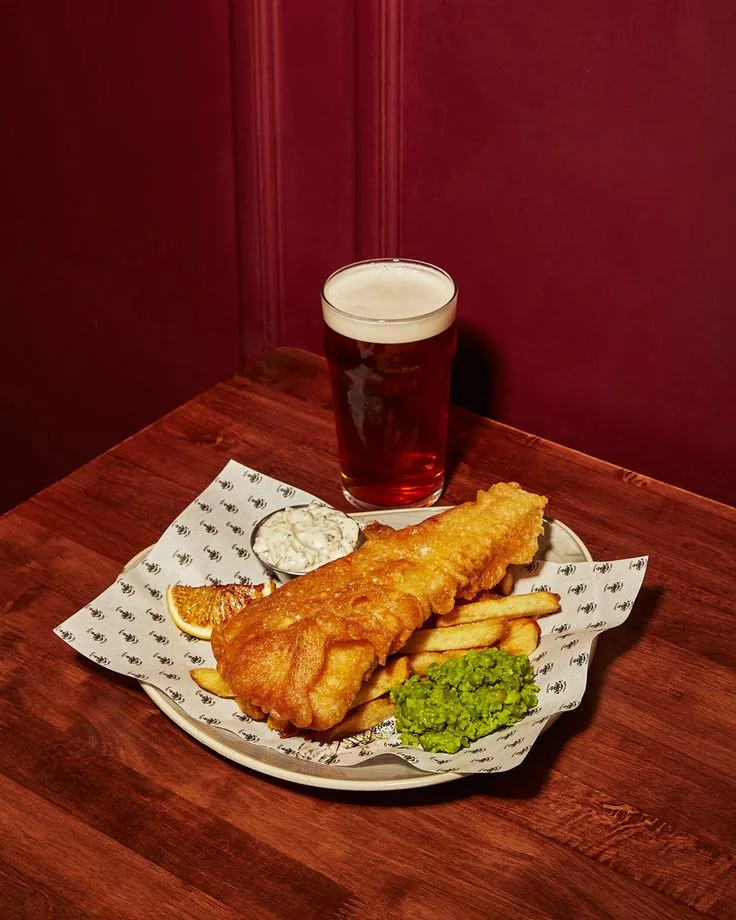 Fish and chips served with a pint in a warm pub setting