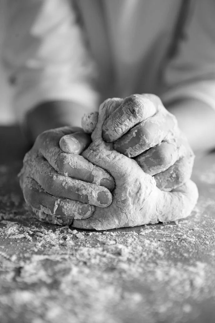 Floured hands working dough in black and white