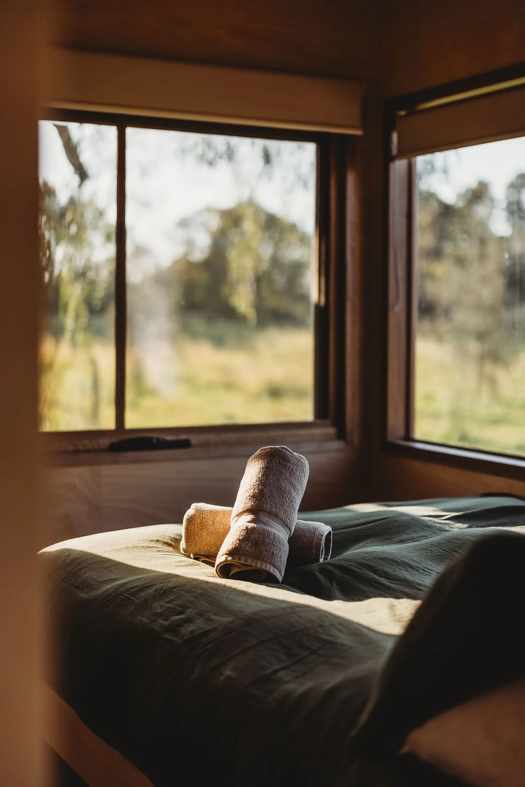 Rolled towels on a bed in a warm cabin with countryside views