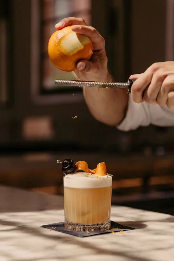 Cocktail finished with fresh orange zest in a warm hospitality setting
