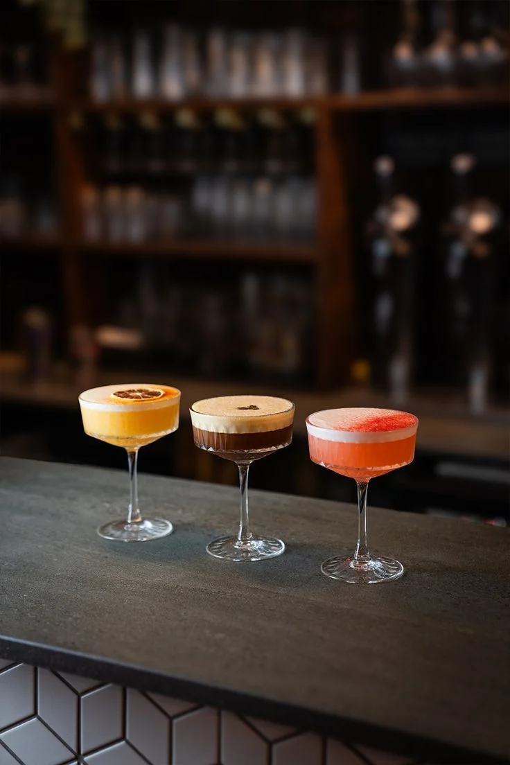 Three colourful cocktails presented on a modern hotel bar counter