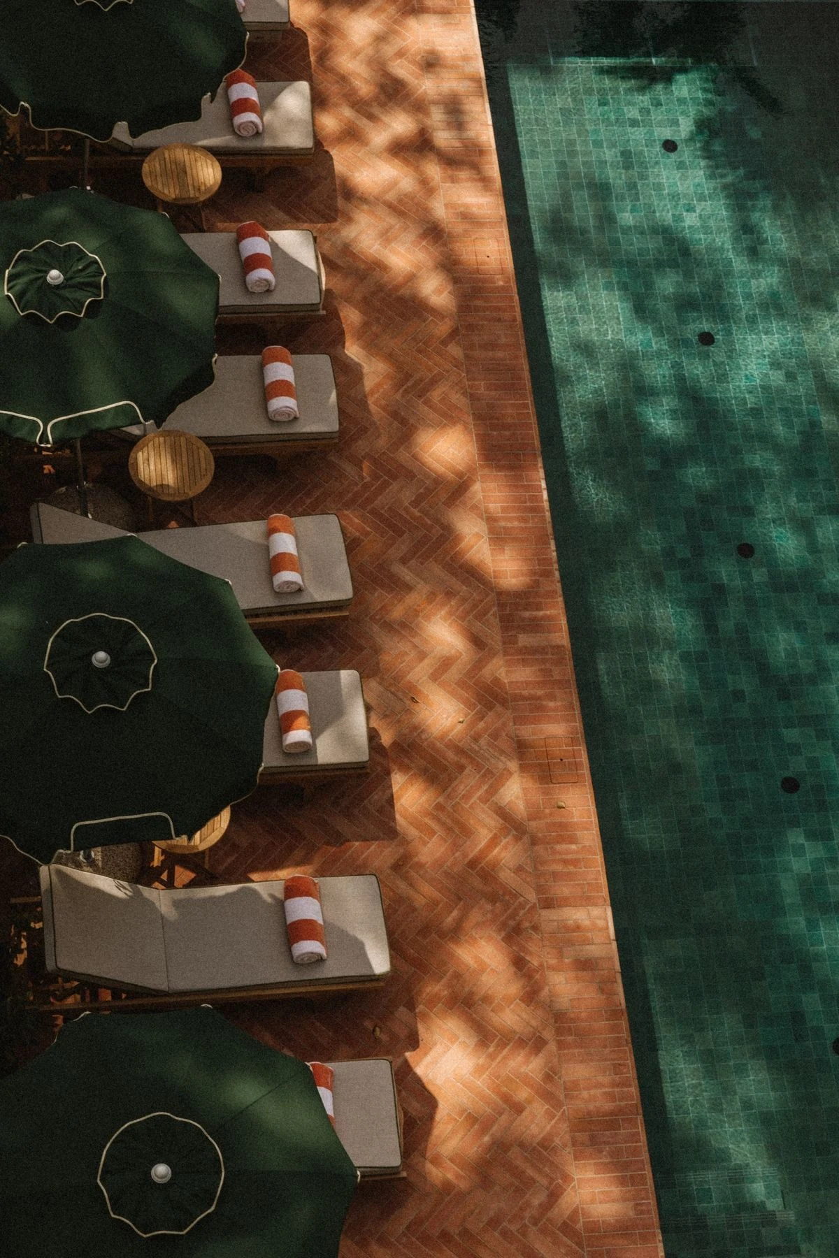 Aerial view of a hotel pool, green parasols and sun loungers on Isola di San Pietro in Sardinia