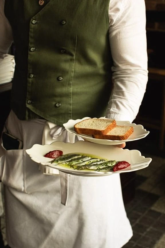 Waiter carrying plated dishes in a restaurant on Isola di San Pietro in Sardinia