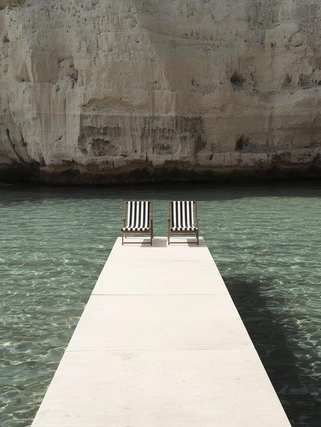 Private jetty with two deckchairs over clear water on Isola di San Pietro in Sardinia