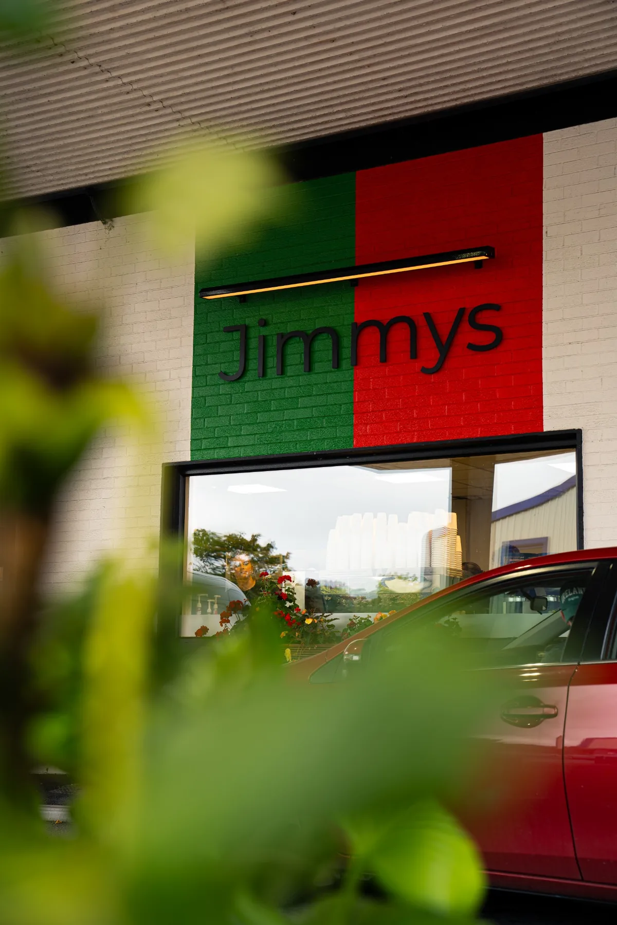 Jimmys facade and branding photographed through green foliage