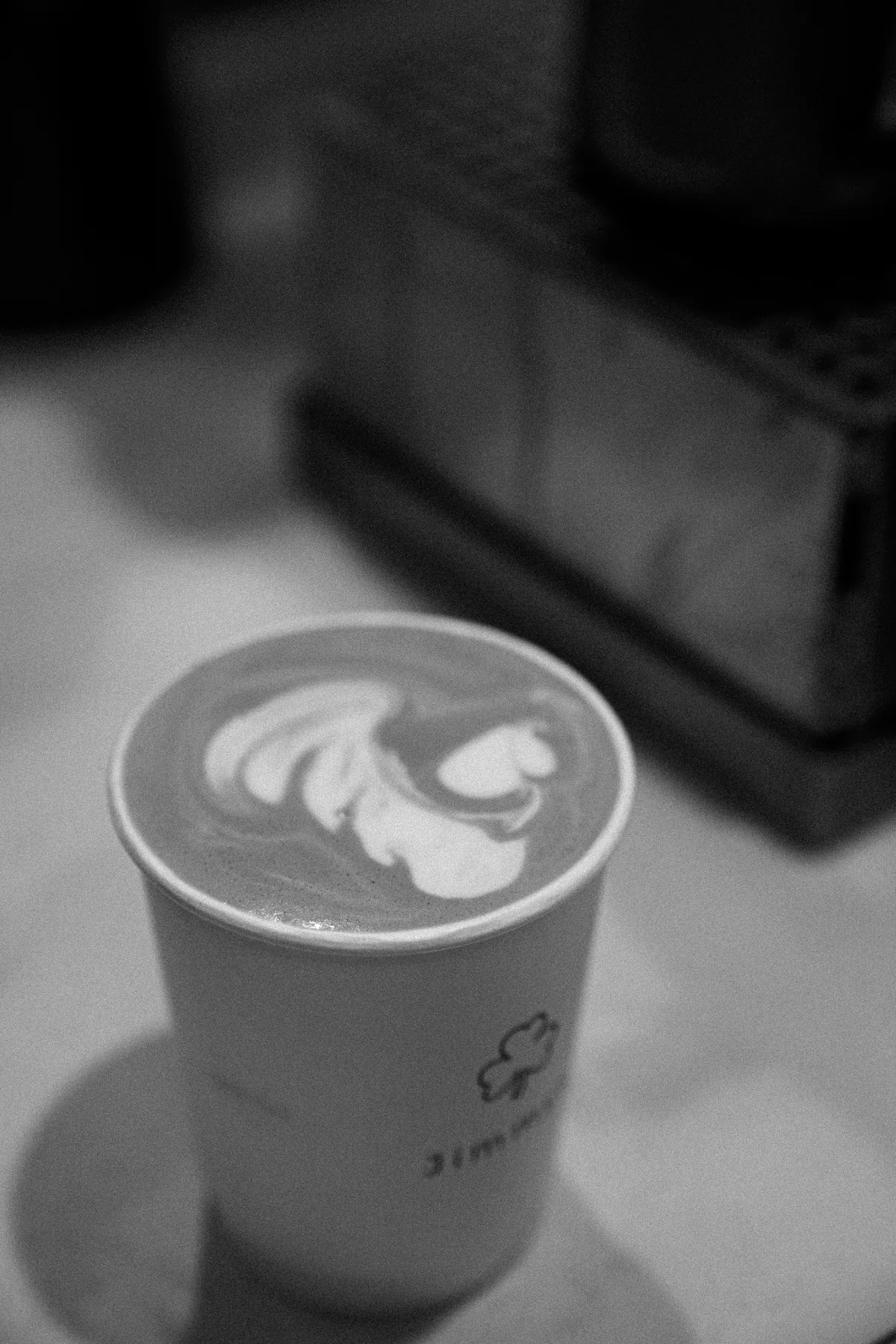 Black and white editorial detail of latte art in a Jimmys cup