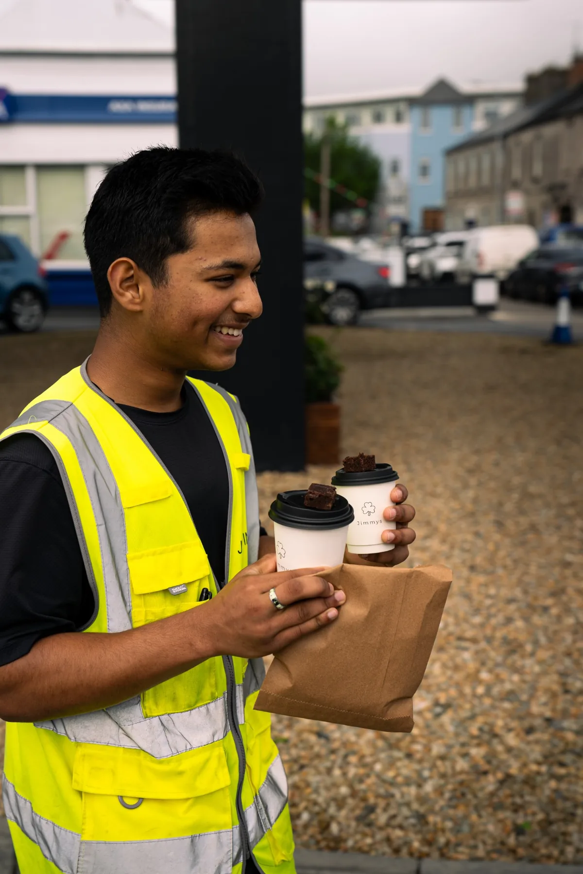 Jimmys staff member carrying takeaway coffees and an order bag