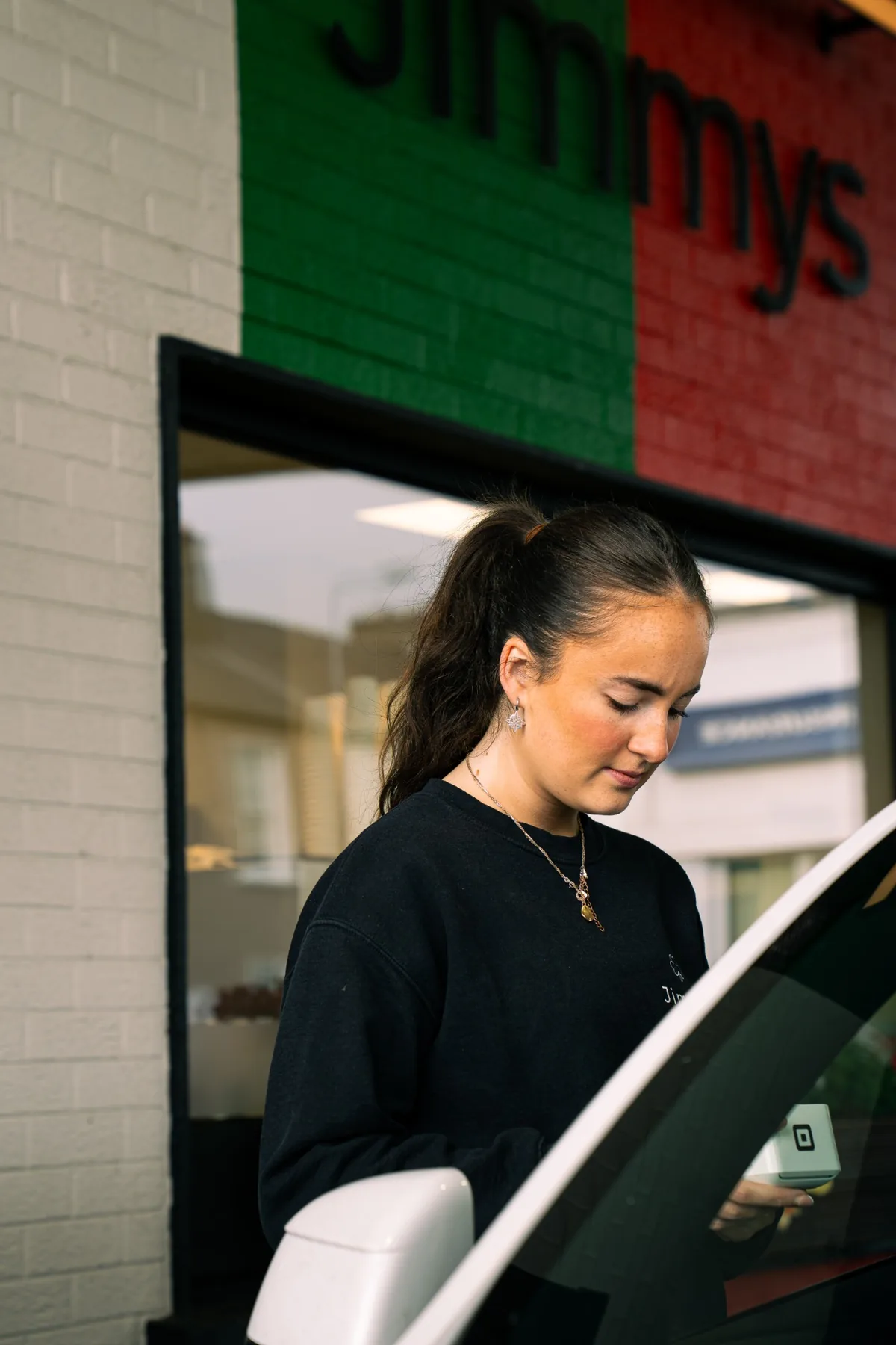 Jimmys team member taking payment beside a customer car