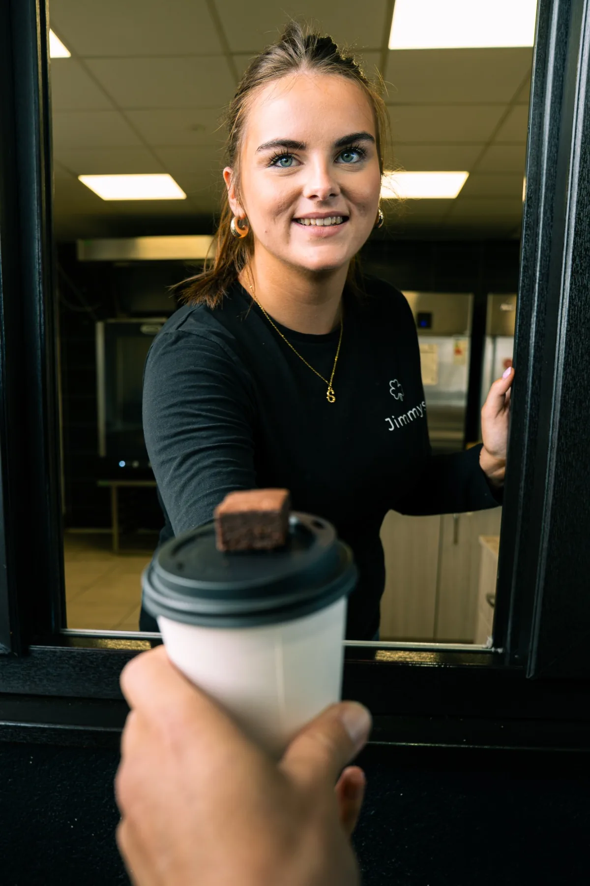 Jimmys barista handing a branded takeaway coffee through the window