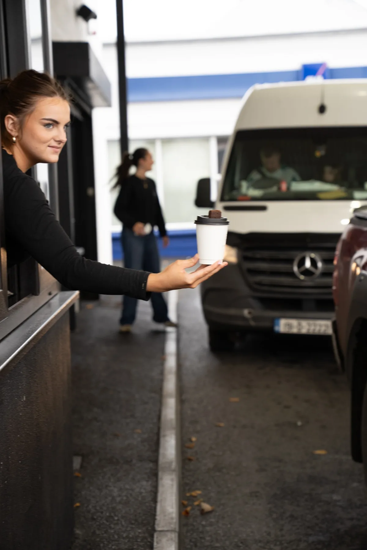 Jimmys barista handing a coffee to a customer at the drive thru