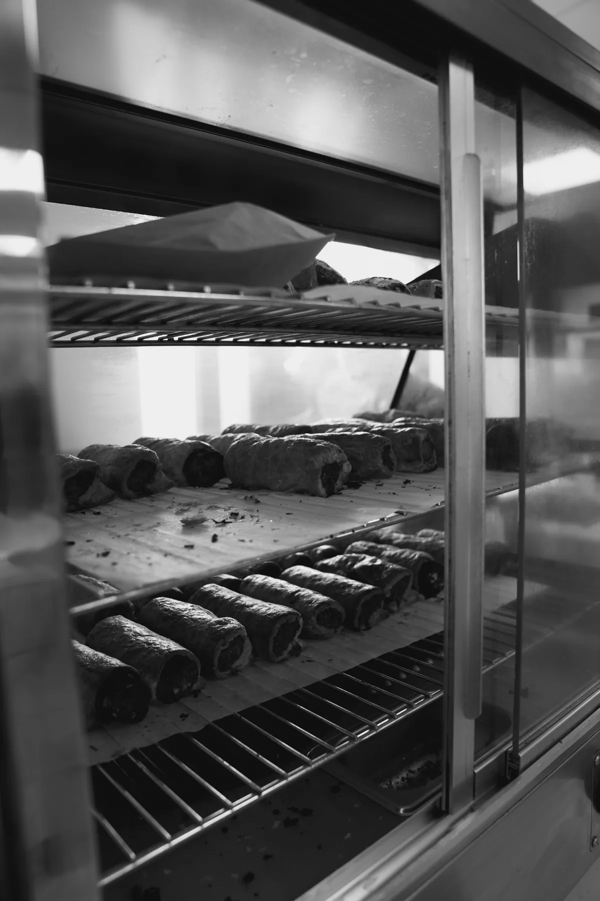 Black and white bakery display of fresh sausage rolls at Jimmys