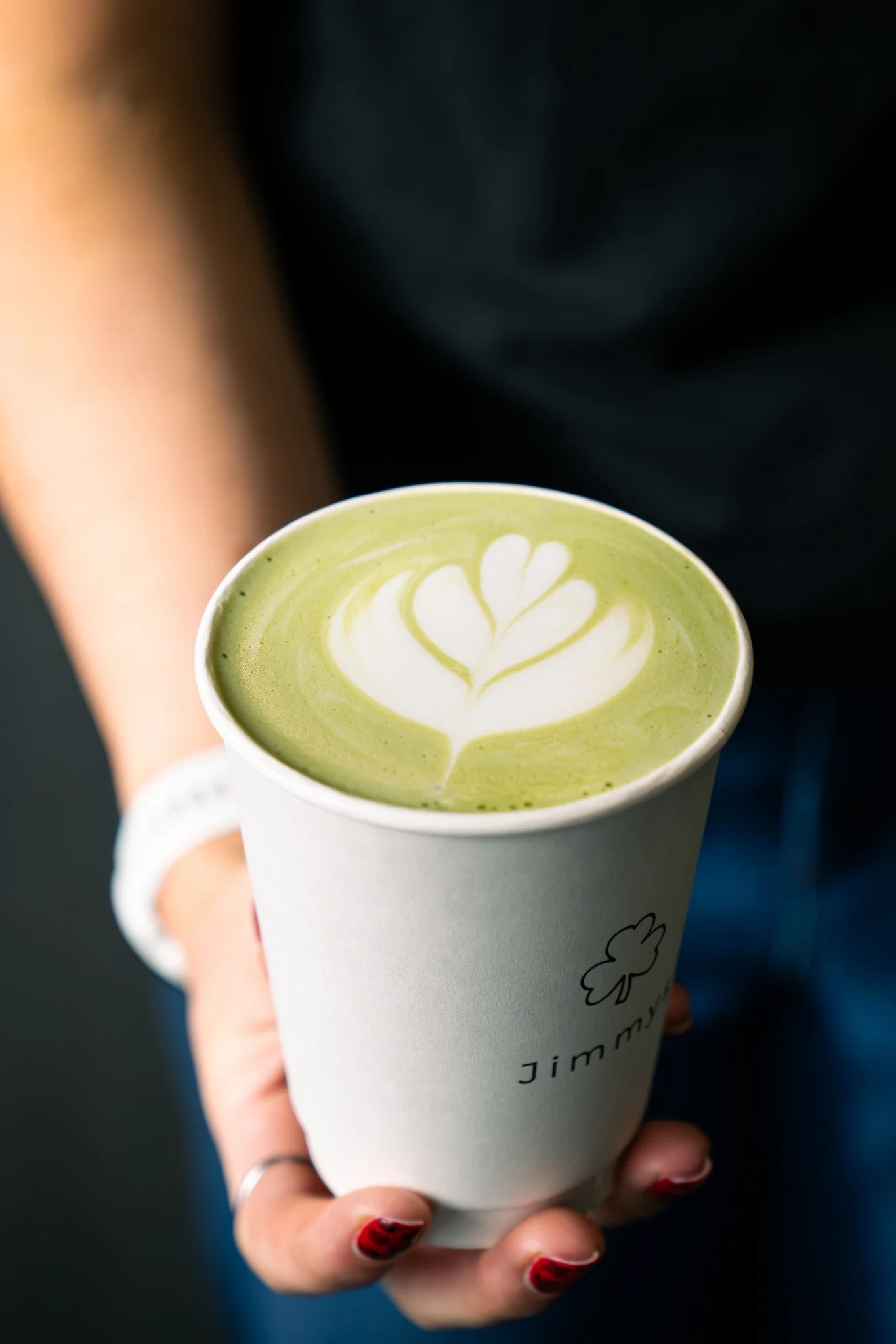 Matcha latte with leaf art in a Jimmy’s takeaway cup