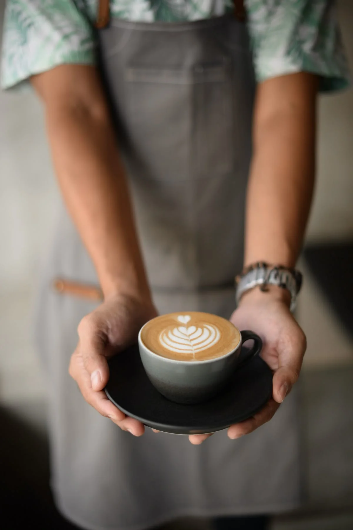 Barista presenting a finished latte with leaf art