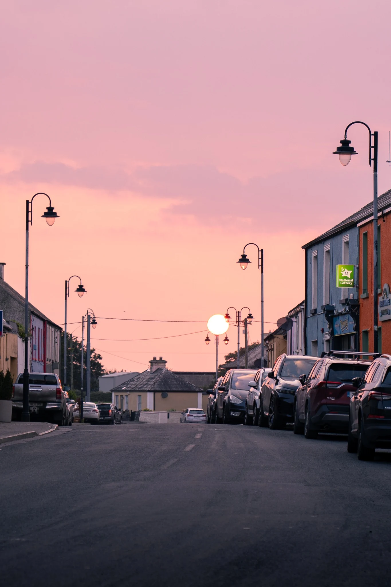 Irish village street glowing under a pink sunset sky