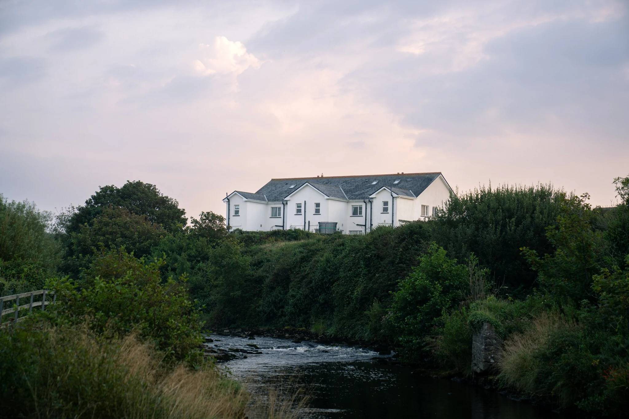 White house above a river surrounded by green Irish landscape