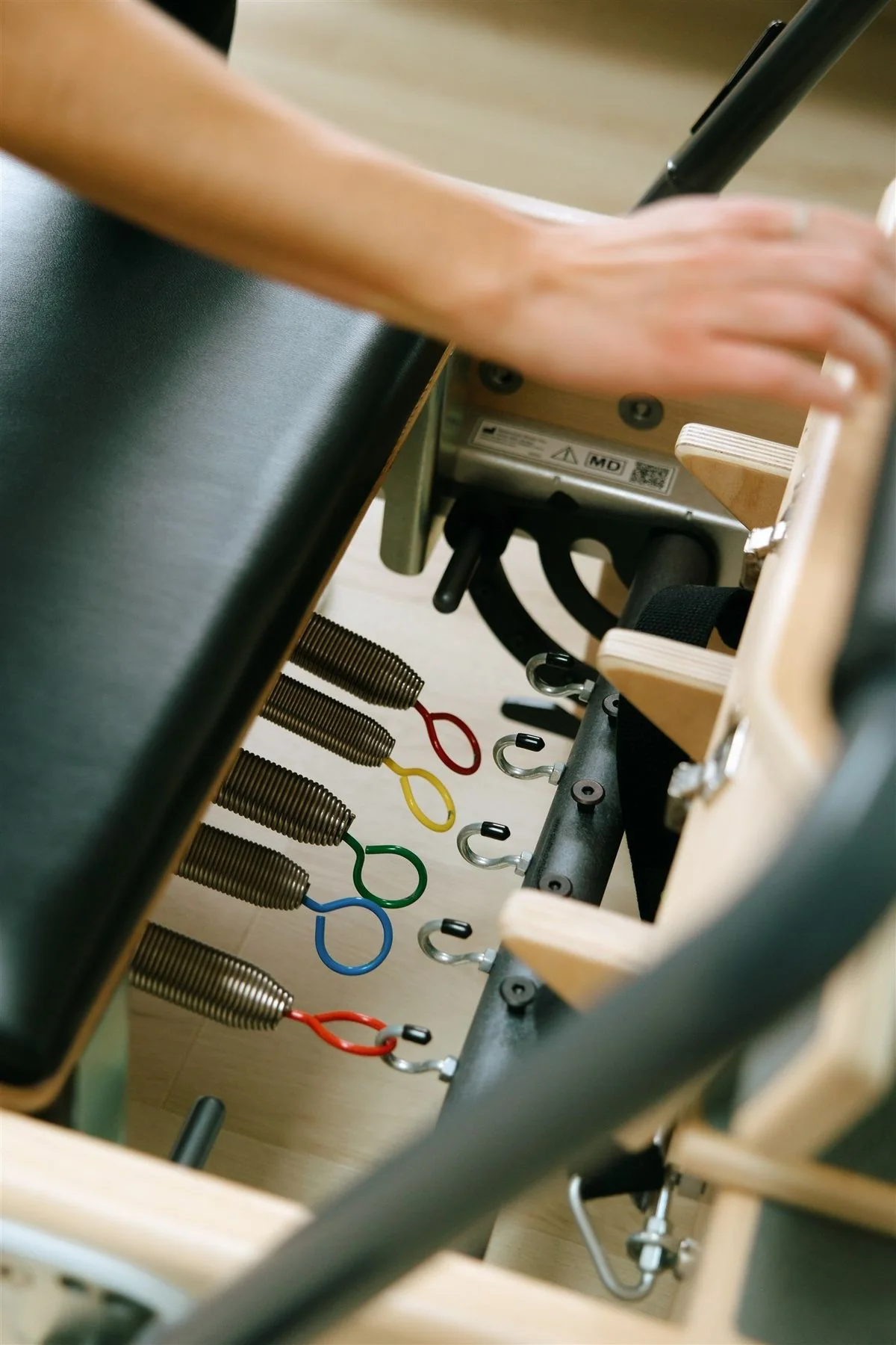 Hands adjusting the springs on a Pilates reformer