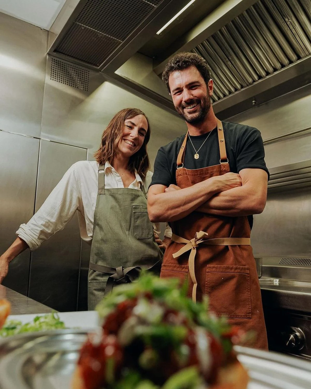 Two chefs smiling together in a professional kitchen