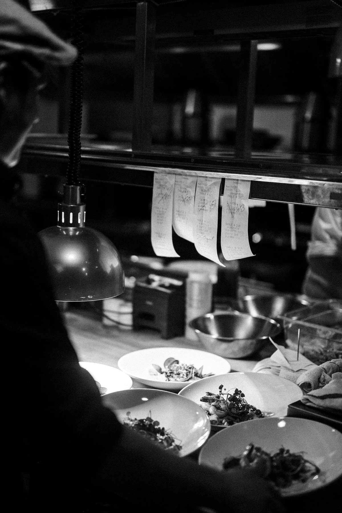 Plated dishes waiting at the restaurant pass in black and white