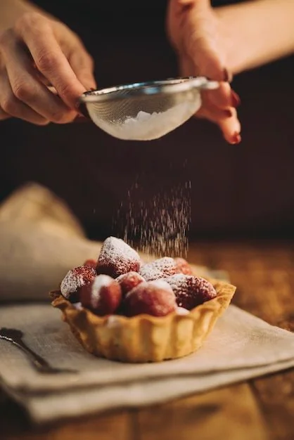 Finishing a fruit tart with a dusting of sugar